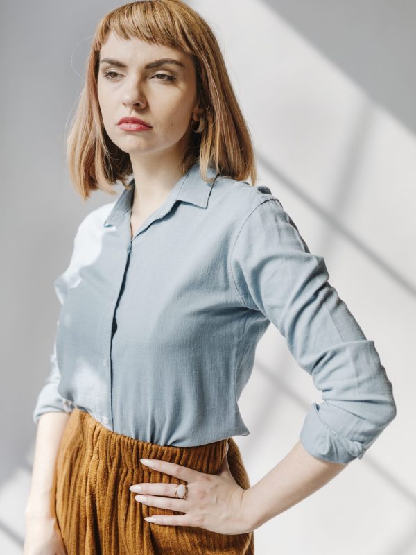 Woman in a blue shirt by the white wall