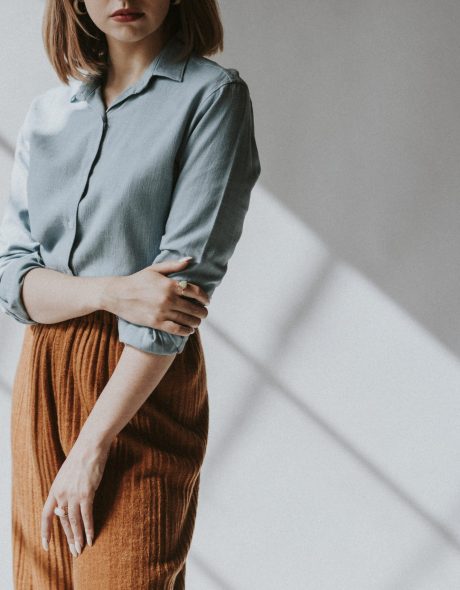 Woman in a blue shirt by the white wall