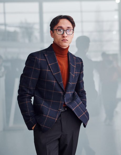 Young business man in luxury suit and formal clothes posing for the camera indoors.